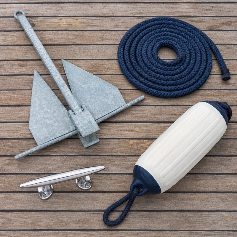 Boat anchor, dock line, cleat and fender on a wooden deck